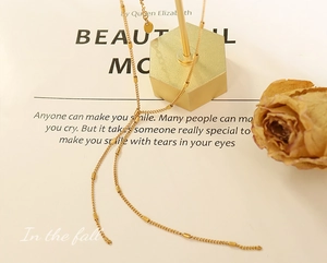 Close-up of golden geometric Y-necklace with cylindrical tubes on a hexagonal display