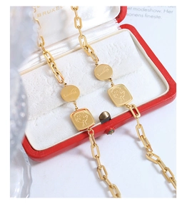 Détail du pendentif doré Lucky et de l'icône fille sur un bracelet à maillons rectangulaires