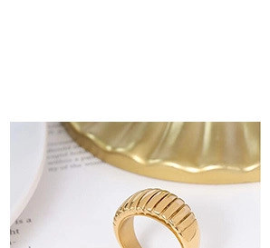 Detail of a vintage golden ring featuring a wide vertical ribbed industrial texture