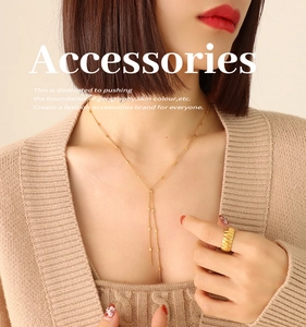 Detailed view of a gold-toned tassel Y-necklace and textured wide ring on a model