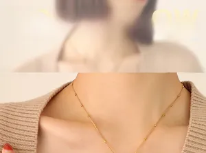 Detail of elegant gold tassel necklace with cylindrical beads worn by a model