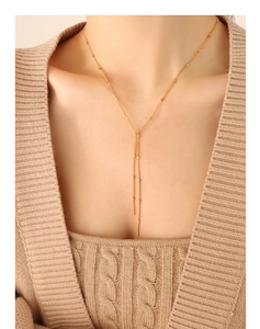 Close-up of elegant 18K gold Y-shaped fringe necklace on a knitted sweater