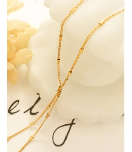 Detailed macro view of a gold-plated thin chain with geometric cylindrical beads