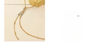Detail of a gold Y-lariat necklace with cylindrical metal beads on a minimalist fine chain