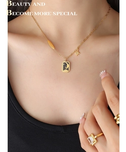 Détail du collier avec pendentif rectangulaire étoile et lune et bague dorée assortie