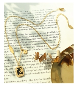 Détail du collier pendentif lune étoile plaqué or 18K sur des pages de livre vintage