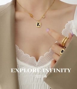 Détail du collier avec pendentif étoile lune dorée et bagues cœur noir sur tenue chic