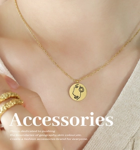 Détails d'un collier en acier titane doré avec pendentif portrait et bague texturée