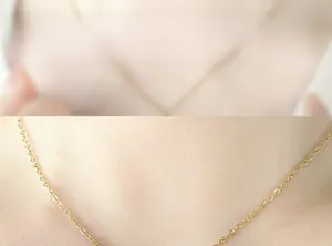 Gros plan d'un collier en chaîne fine dorée en acier titane porté par un mannequin