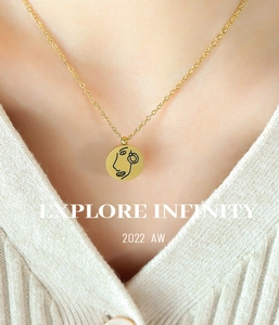 Gros plan d'un pendentif rond doré avec gravure de visage minimaliste sur chaîne fine