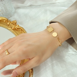 Bracelet doré avec pendentif Lucky et bague minimaliste portés au poignet d'un mannequin