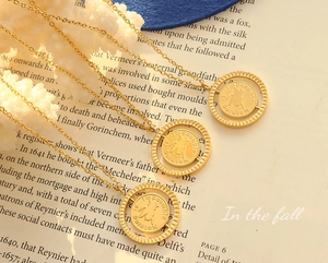 Detail of gold pig pendant necklace with Nothing is Impossible engraving on book pages