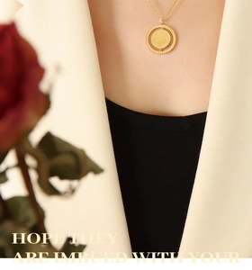 Close-up of a vintage double-sided pig coin pendant necklace worn with a white blazer