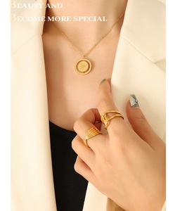 Detail of vintage gold plated titanium steel pig coin necklace and twisted knot rings