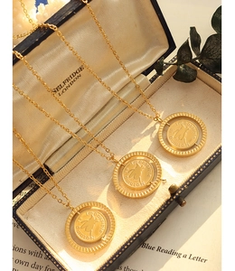 Macro detail of rotating gold pig coin necklaces with Impossible is Nothing engraving