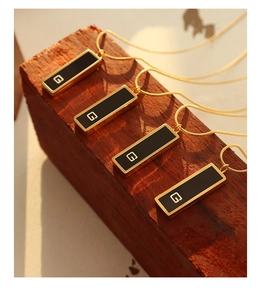 Detailed view of rectangular black enamel G pendants on elegant gold snake chains