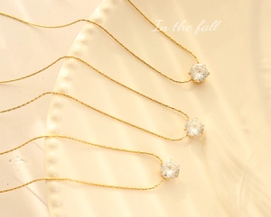 Close-up of three gold cubic zirconia necklaces with six-claw setting on a white plate
