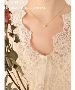 Close-up of elegant gold necklace featuring a single round zircon pendant on a model