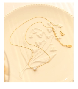 Close-up of 18K gold necklace featuring a round zircon pendant and K18 hallmark tag