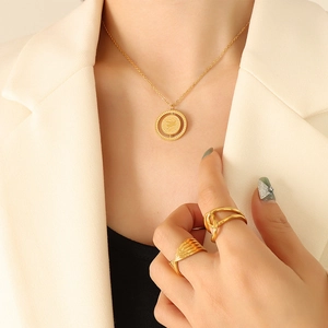 Minimalist gold coin necklace and twisted rings set worn with an elegant suit