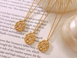 Detail of three 18K gold plated irregular pendant necklaces with lava texture on book page