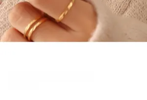 Close-up of three stacked minimalist irregular gold-plated titanium steel rings on a finger