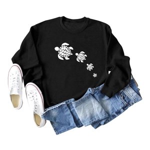 Flat lay of black sweatshirt featuring four white geometric sea turtles with blue jeans