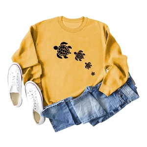 Flat lay of mustard yellow sweatshirt with turtle print, denim shorts and sneakers
