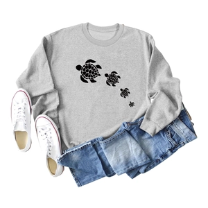 Flat lay of gray long sleeve sweatshirt with turtle print next to white canvas shoes