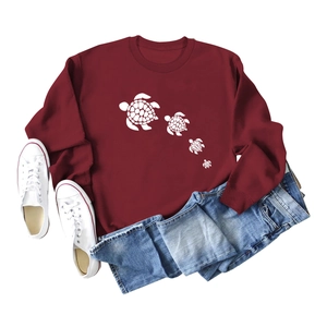 Detailed view of the cute white turtle silhouette print on dark red cotton sweatshirt