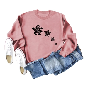 Pink crewneck sweatshirt with cute turtle print paired with blue jeans and canvas shoes