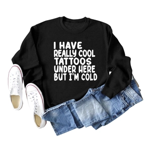 Close-up flat lay of black sweatshirt with white text I Have Really Cool Tattoos Under Here