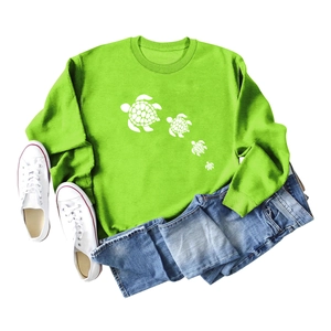 Flat lay of green sweatshirt with white sea turtle print, denim shorts and sneakers