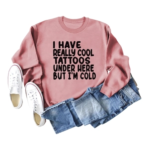 Flat lay of pink sweatshirt with humorous text, blue jeans and white canvas sneakers