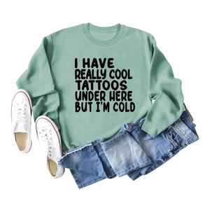 Flat lay of a mint green sweatshirt with funny text paired with jeans and sneakers