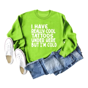 Flat lay of bright green crewneck sweatshirt with tattoos text, jeans and sneakers