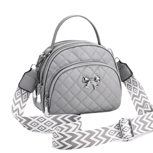 Grey quilted crossbody bag with silver bow detail and geometric patterned shoulder strap