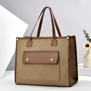 Detail showing high-capacity canvas tote with brown leather trim and golden metal snaps