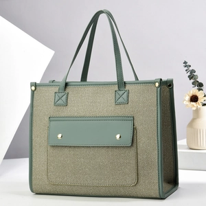 Detail of sage green canvas tote bag with contrast faux leather pocket and metallic buckle