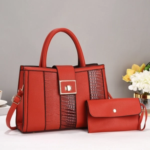 Dettaglio della borsa rossa con trama coccodrillo, fibbia dorata e pochette