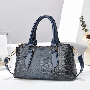 Elegant navy blue crocodile embossed satchel with gold hardware on a modern decor setup