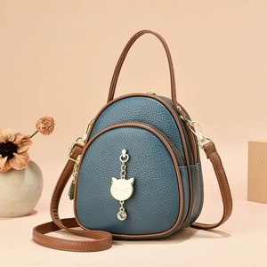 Three-layer navy lychee leather crossbody bag with cat pendant and brown trim contrast