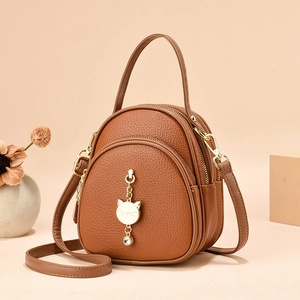 Brown lychee leather mini crossbody bag with multiple zippers and a gold cat charm