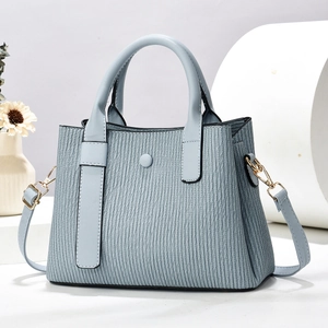 Light blue pleated tote bag with round handles and gold hardware on white pedestal