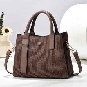 Close-up of deep brown pleated texture handbag with gold hardware and leather handles
