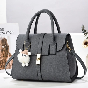 Détail du sac cabas gris tissé avec fermoir doré rotatif et pendentif d'agneau en peluche