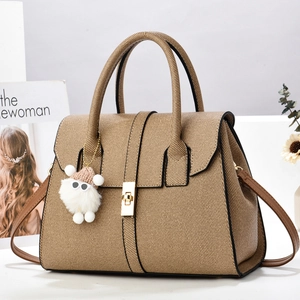 Sac à main tissé marron avec fermoir doré, bandoulière et breloque peluche sur fond magazine