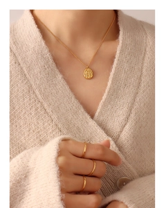 Close-up of gold geometric shell-textured pendant necklace and minimalist stackable rings
