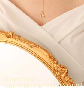 Close-up of gold plated stainless steel H letter pendant necklace worn by a model