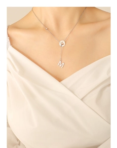 Detail of silver Y-shaped tassel necklace with letter M pendant and zircon stone